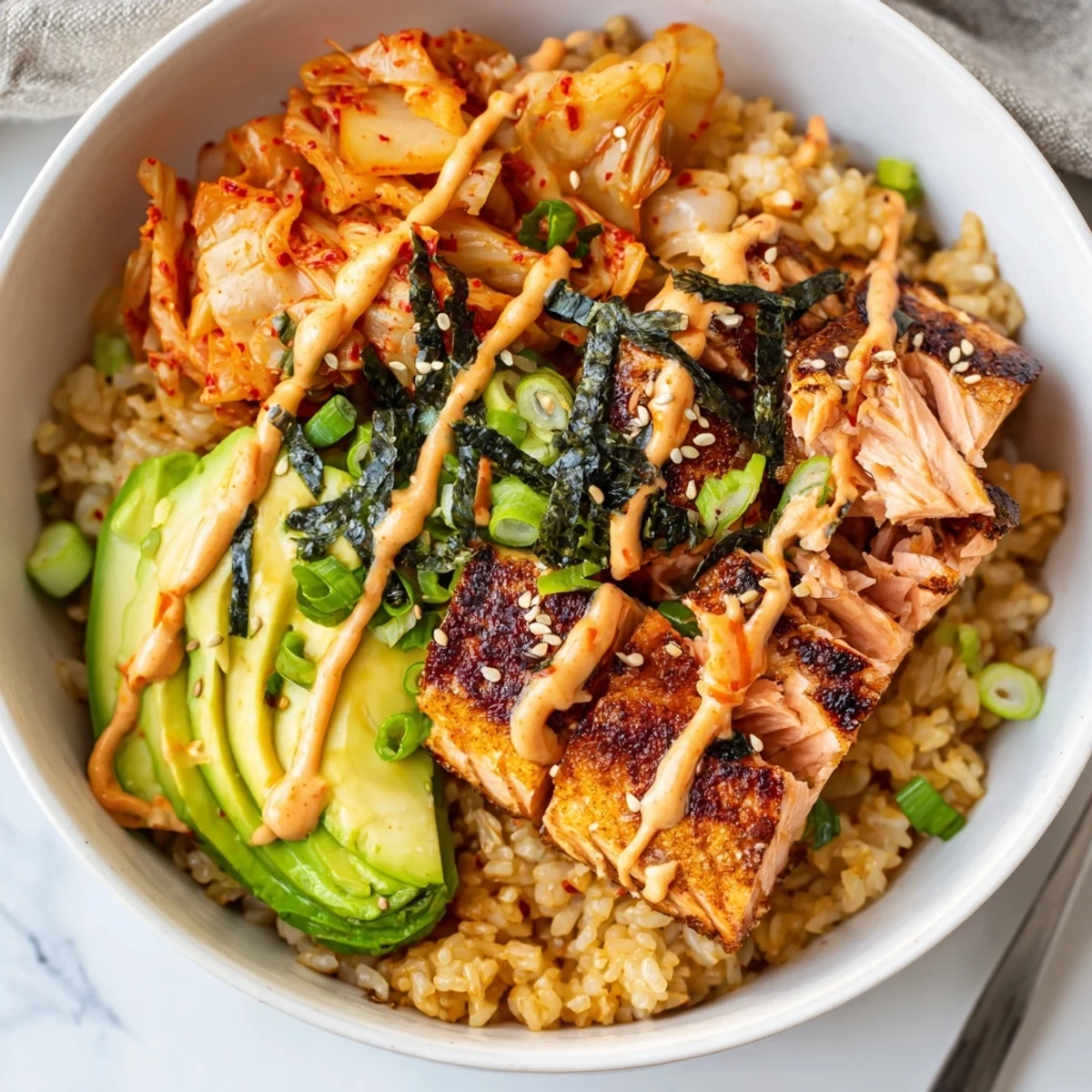 Crispy Salmon Rice Bowl topped with spicy mayo and fresh cucumber slices.  