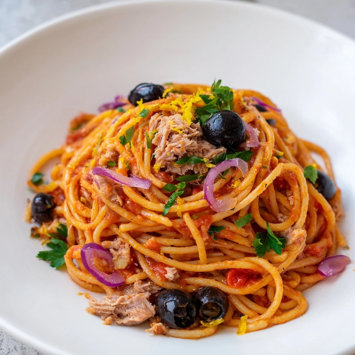 Fragrant Pasta with Tuna, Olives & Capers, garnished with fresh parsley, looks delicious and inviting on a plate.
