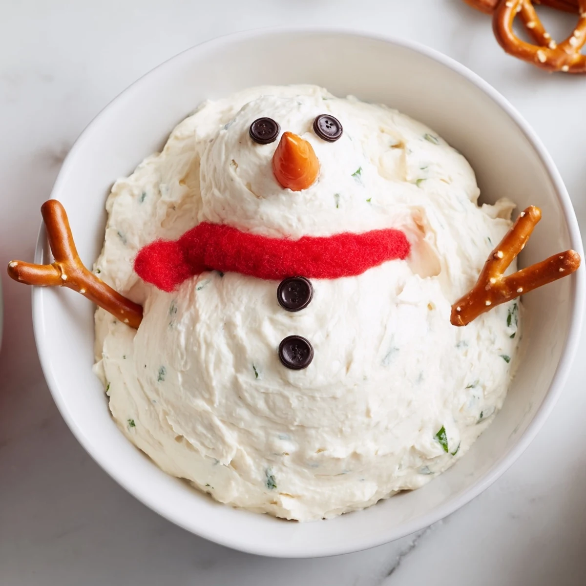 A cheerful view of the melted snowman dip with carrot nose and pretzel arms, perfect for parties.