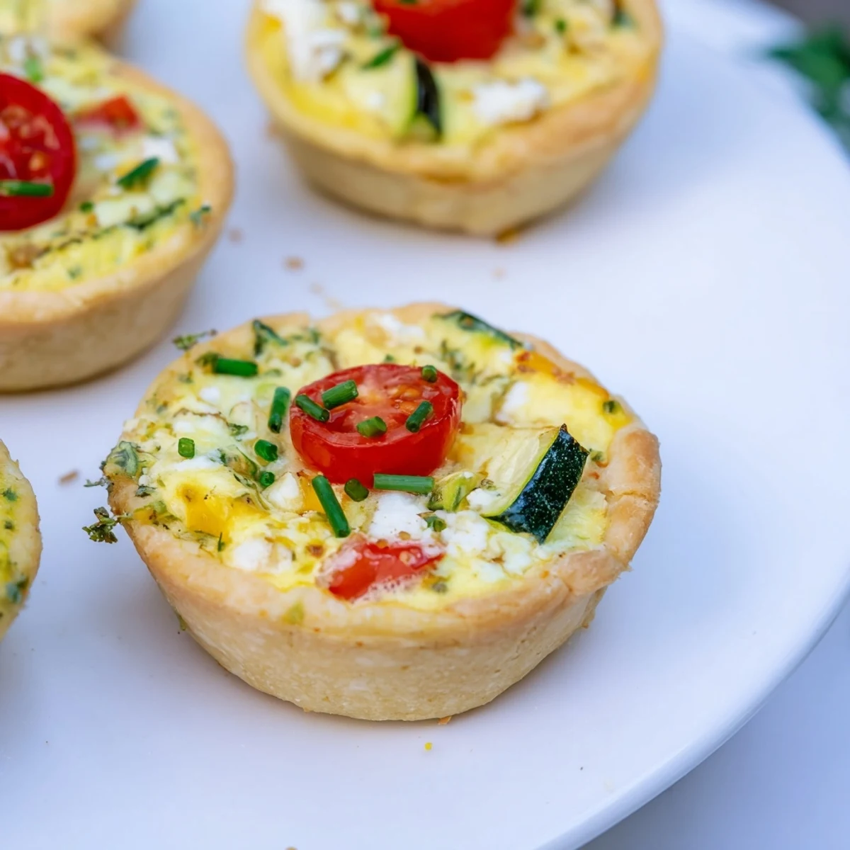 A colorful photo displays homemade Couronne Florale Mini Quiches, filled with spring vegetables and creamy cheese.