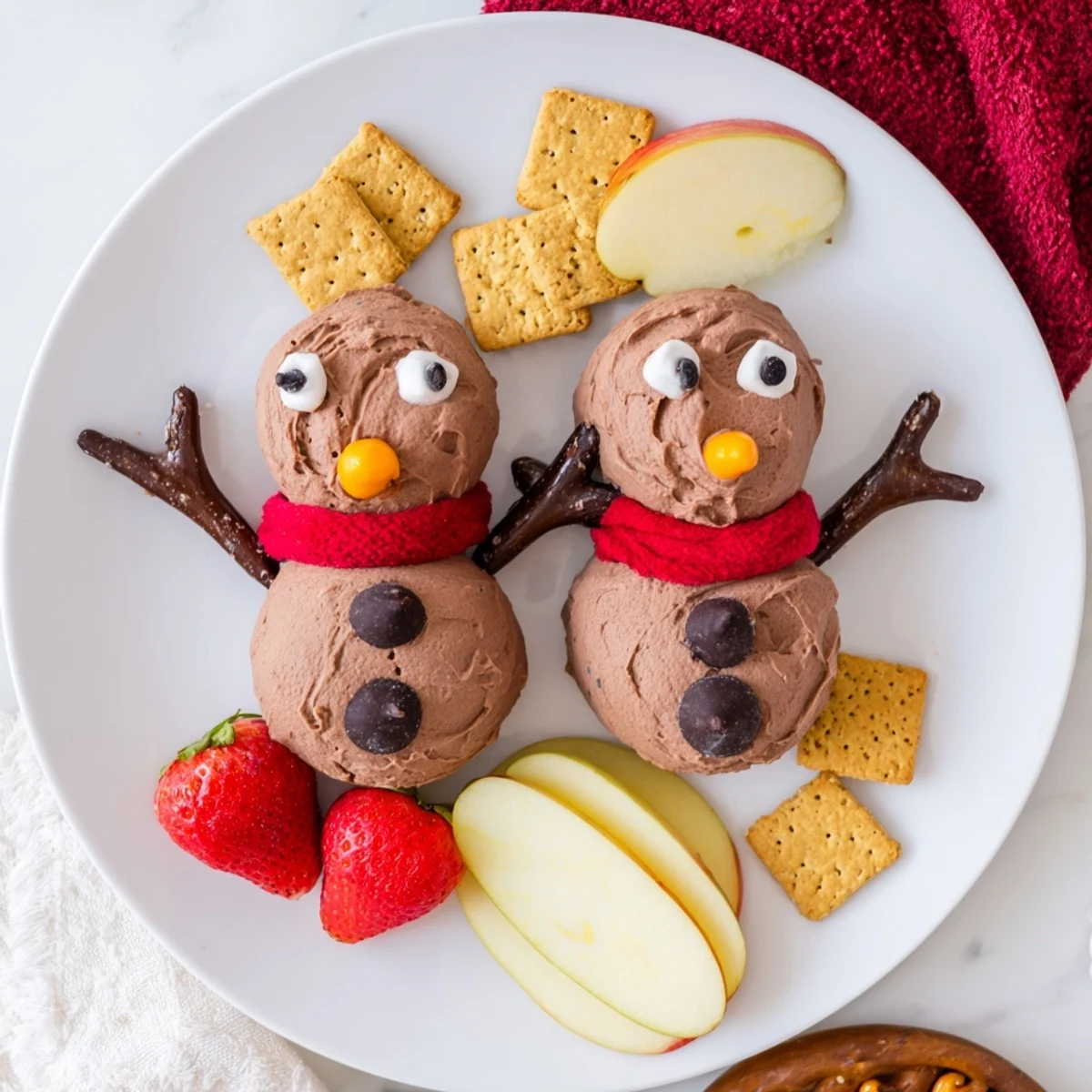 Creamy hot cocoa dip snowman, decorated with mini chips and licorice, perfect for holiday treats.