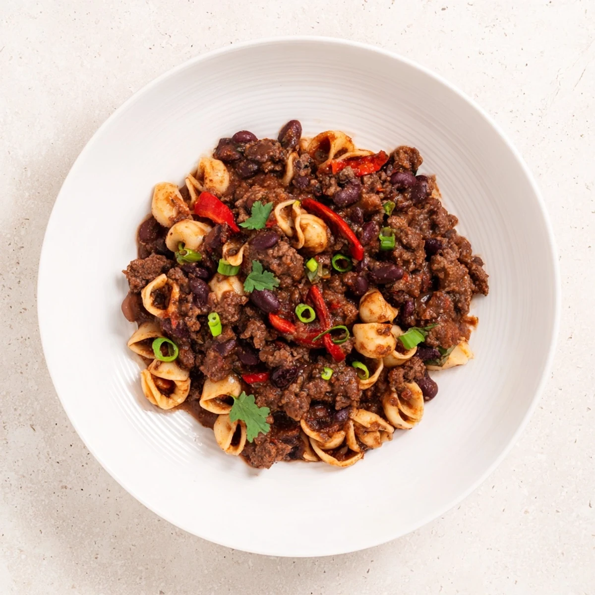 Steaming bowl of one-pot ditalini with hot cocoa chili, garnished with fresh cilantro and green onions.
