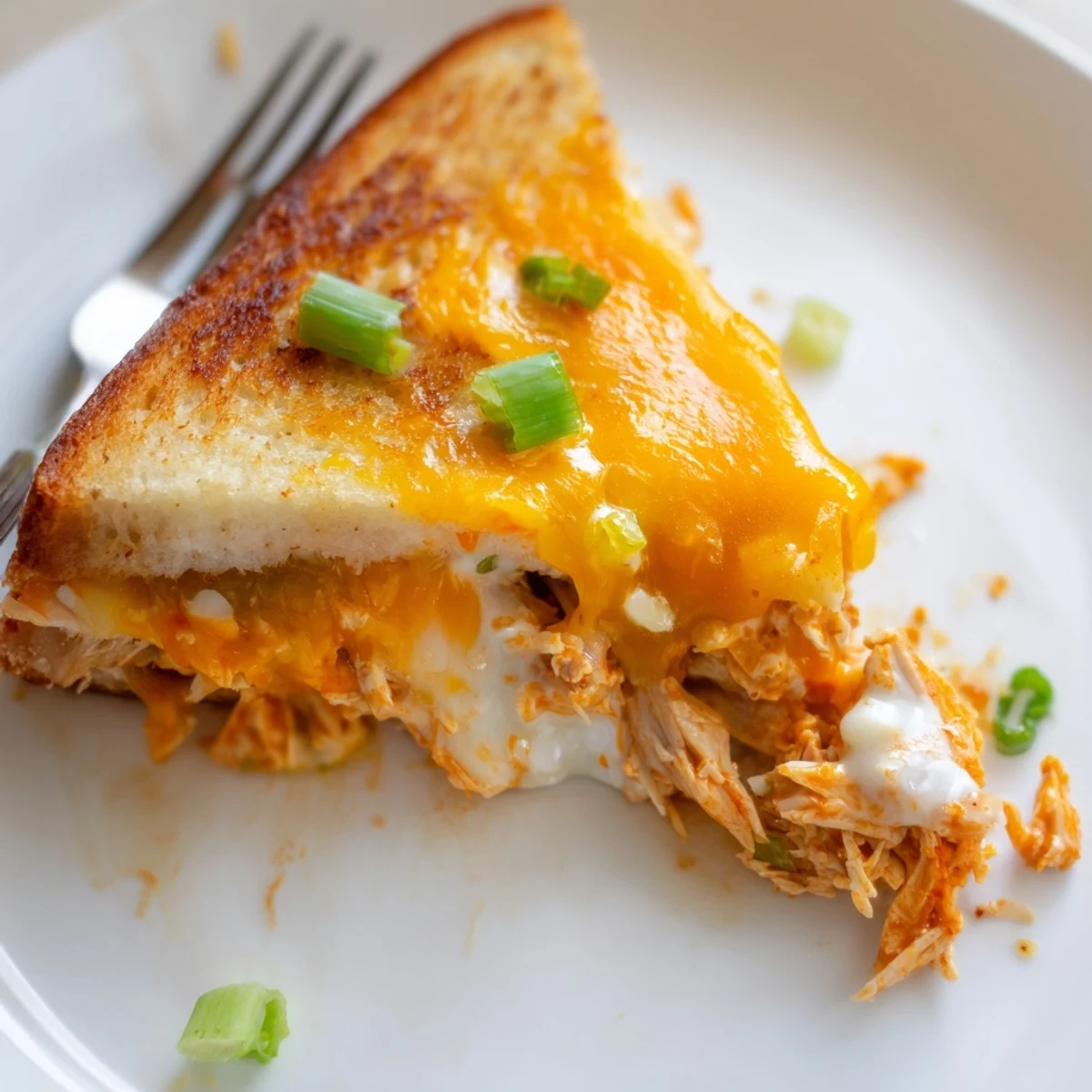 Golden-brown Buffalo Chicken Ranch Grilled Cheese sandwiches sliced to reveal layers of spicy shredded chicken and melted cheese.
