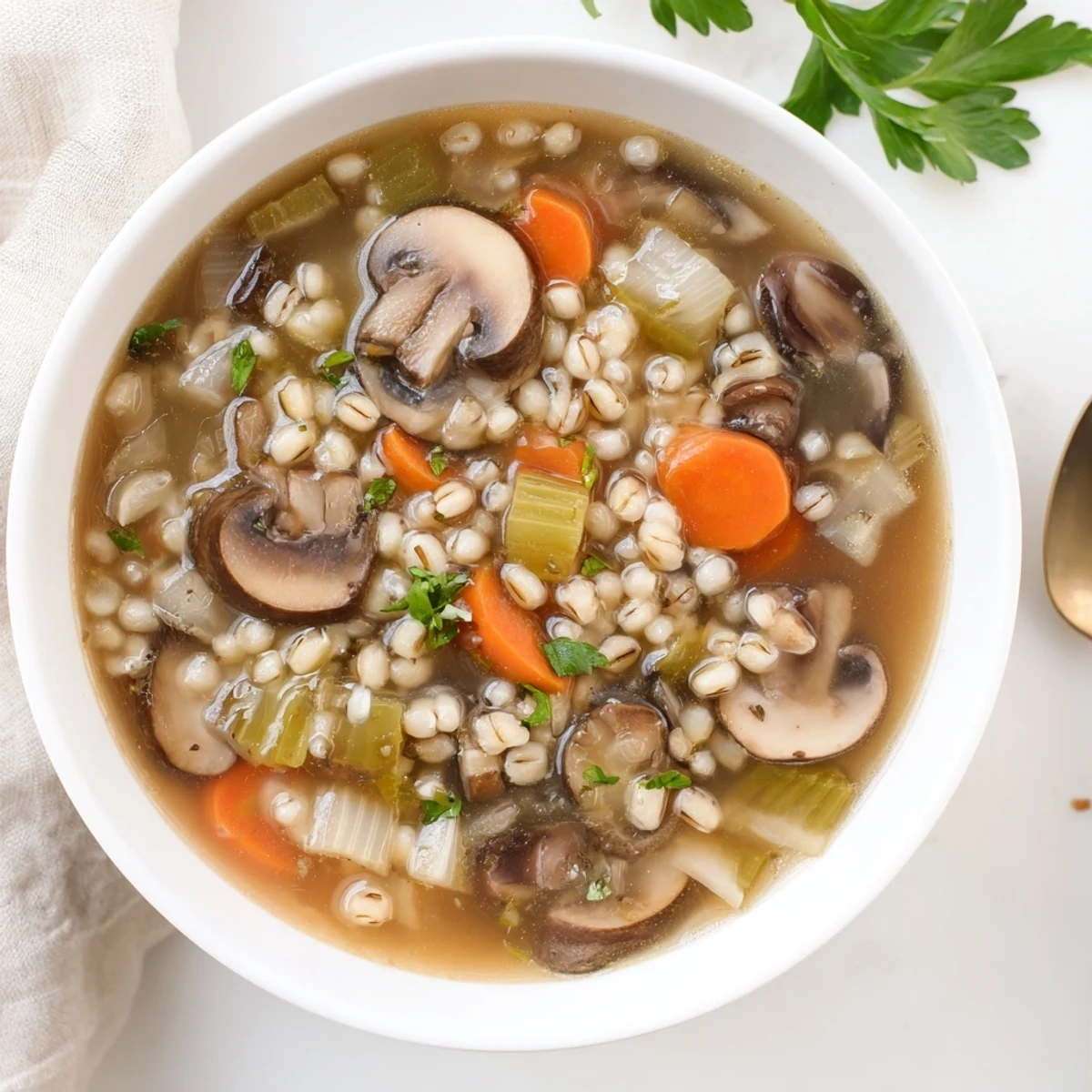 Spoon dipping into a hearty bowl of Mushroom and Barley Soup, steam rising from the savory broth.