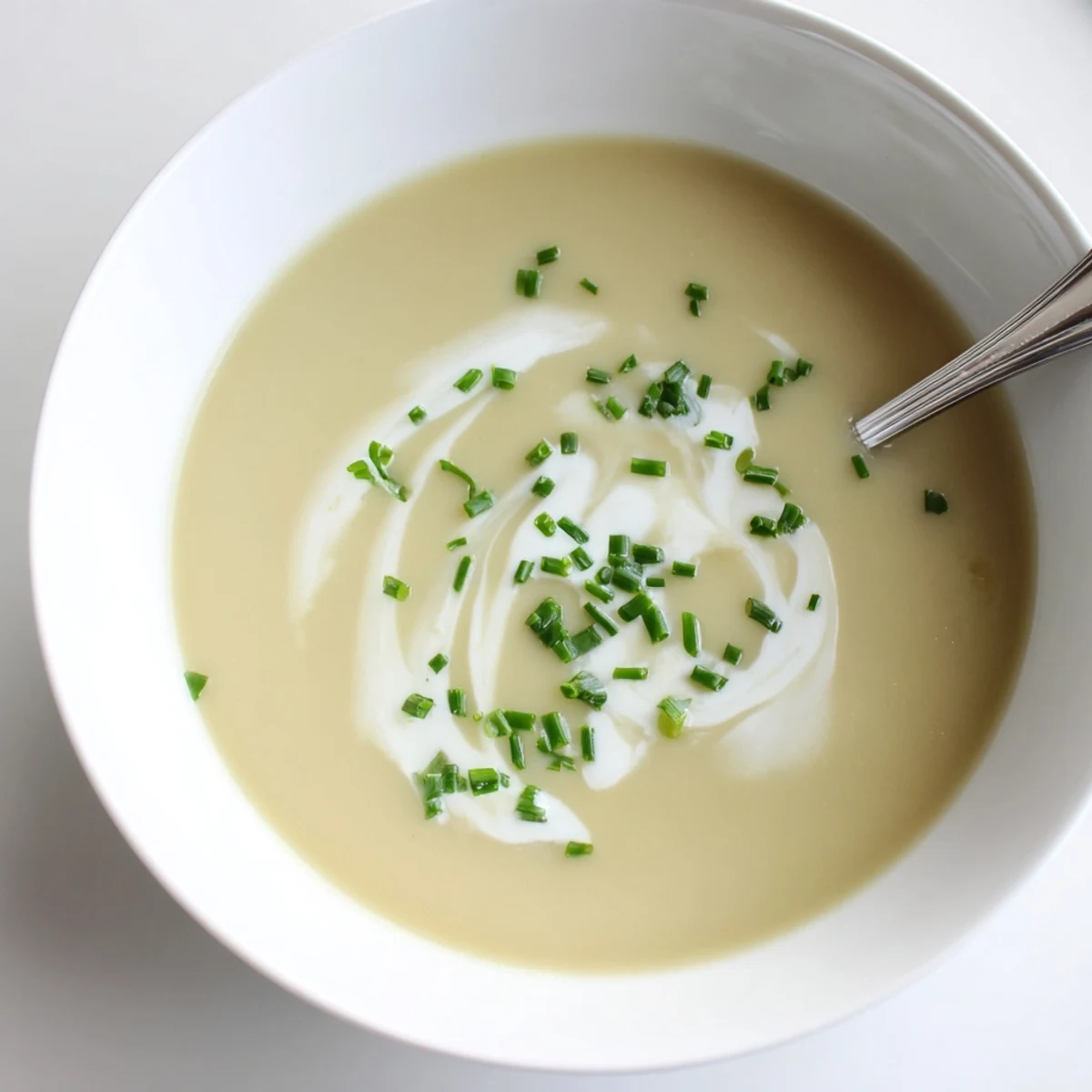 A bowl of velvety celery root bisque, garnished with microgreens and paired with crusty bread for dipping.