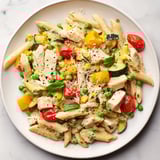 A close-up view of The Last Bite Chicken Pasta, showing colorful veggies and melted cheeses.