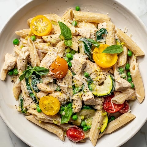 Steaming plate of The Last Bite Chicken Pasta, with creamy sauce and fresh basil garnish.