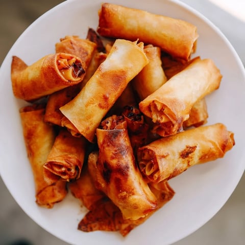 Golden-brown Tinis Mac and Cheese Lumpia Rolls, a crispy exterior revealing creamy, cheesy goodness within.
