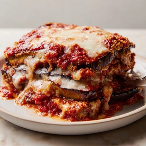 Close-up of delicious Eggplant Parmesan Casserole, browned cheese and savory layers hinting at warm flavors.