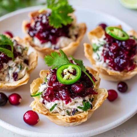 Golden tart shells filled with zesty Cranberry Jalapeño Dip, a perfect holiday appetizer.  