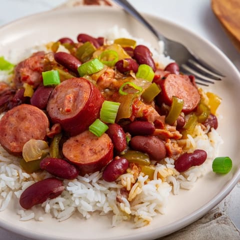 Comforting red beans and rice dish garnished with fresh parsley and hot sauce.  