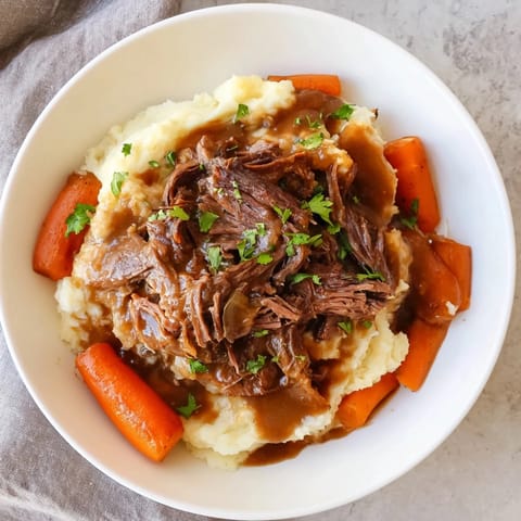 A close-up of a steaming Slow Cooker Pot Roast with vibrant vegetables and creamy potatoes.