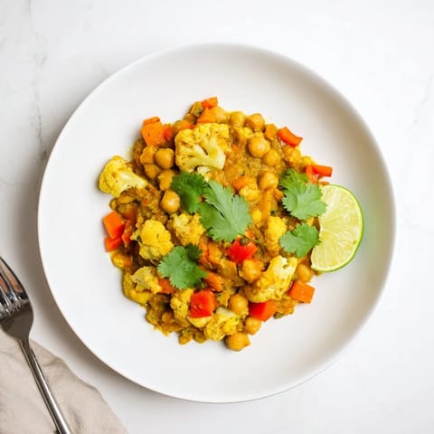 A vibrant close-up showing the rich, spiced sauce in this aromatic curried cauliflower and chickpea stew.
