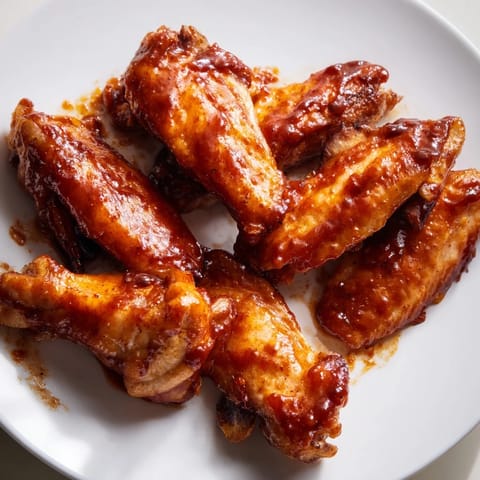 A close-up of delicious baked honey BBQ wings, showing their perfectly caramelized, savory surface.