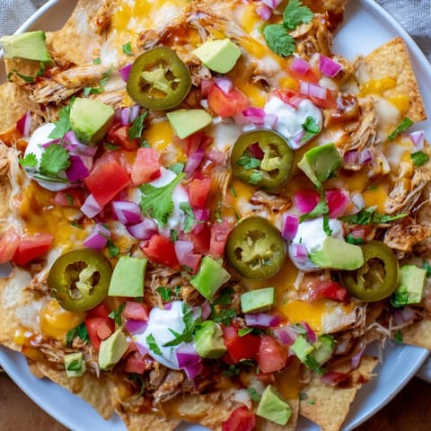 Savory Loaded Nachos: Warm pulled pork atop crispy chips, smothered in creamy queso, ready to eat.